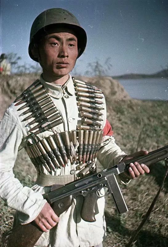 这位解放军战士可谓是美式装备从头到脚。戴着美国M1钢盔，手中拿着M1汤姆森冲锋枪，脖子和身上缠着M2型12.7mm机枪的弹链。